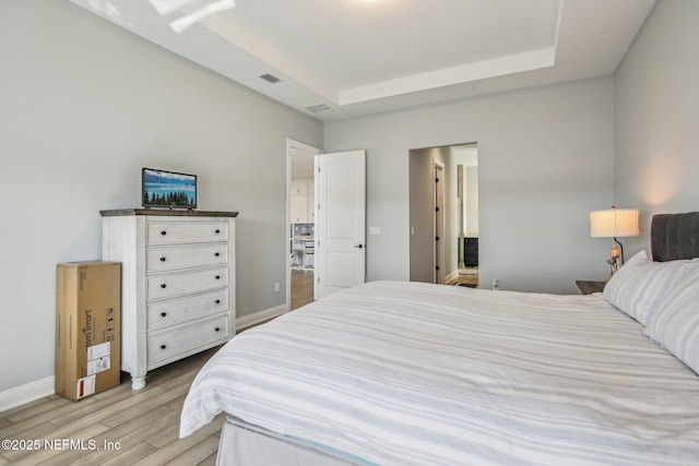 bedroom featuring a raised ceiling and light hardwood / wood-style flooring