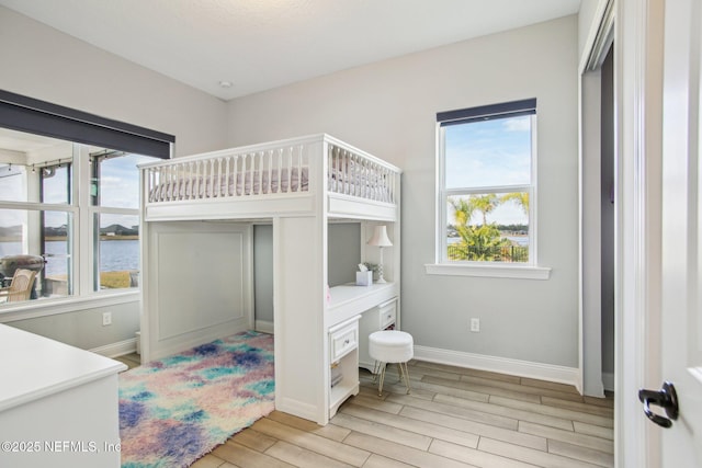 bedroom featuring a water view and light wood-type flooring