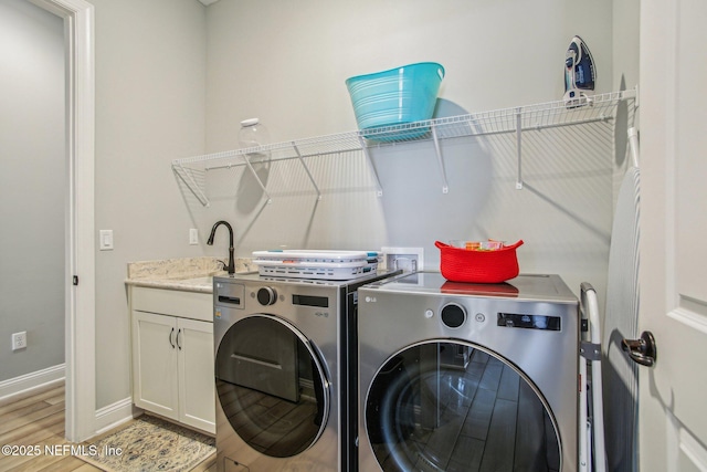 washroom featuring sink, washing machine and dryer, and cabinets