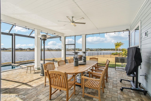 sunroom with ceiling fan and a water view