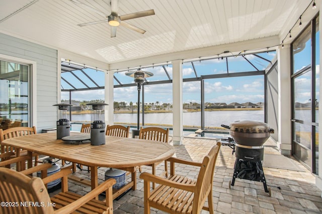 sunroom featuring a water view and ceiling fan