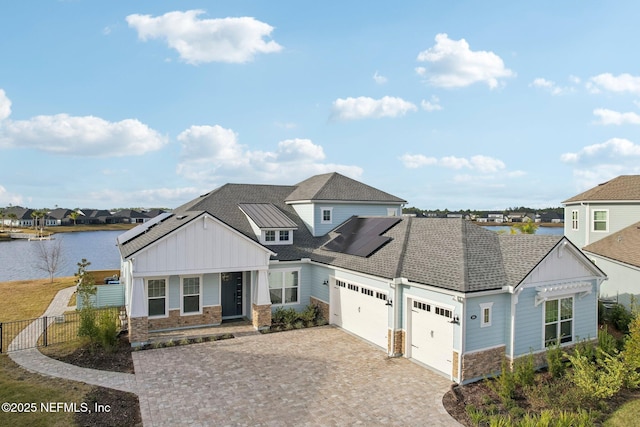 view of front of house with a garage, a water view, and solar panels