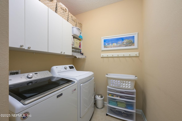 laundry area featuring light tile patterned floors, a textured ceiling, cabinets, and washing machine and clothes dryer