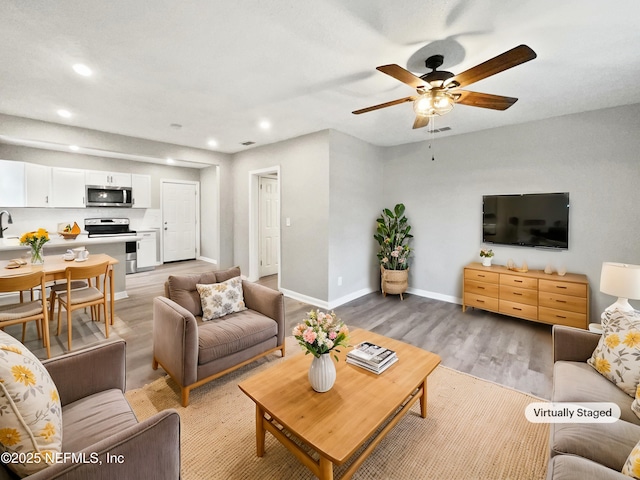 living room featuring ceiling fan and light wood-type flooring