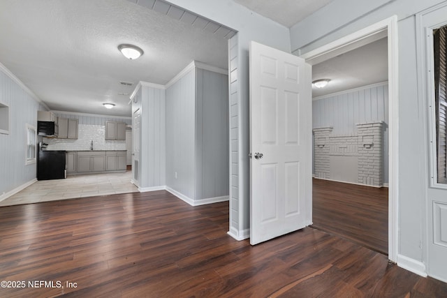 unfurnished living room featuring ornamental molding, dark hardwood / wood-style floors, sink, and a textured ceiling