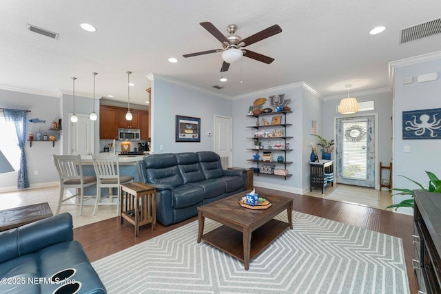 living room featuring ceiling fan, crown molding, light hardwood / wood-style flooring, and a textured ceiling