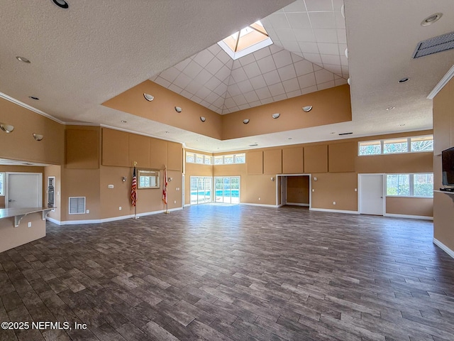 unfurnished living room with a high ceiling, crown molding, dark hardwood / wood-style flooring, and a skylight