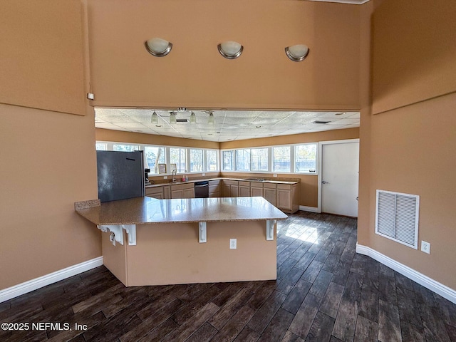 kitchen featuring dishwashing machine, sink, a kitchen breakfast bar, black fridge, and kitchen peninsula