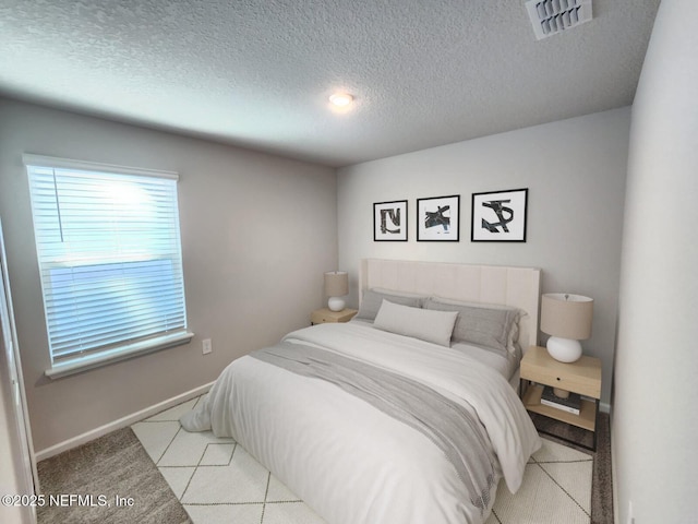 bedroom with light colored carpet and a textured ceiling