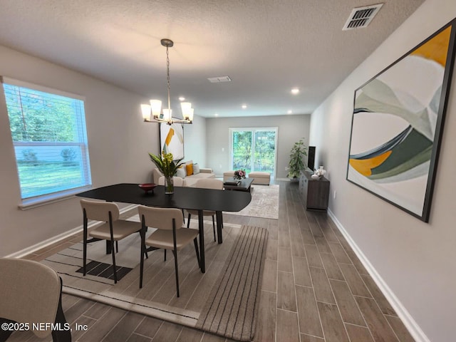 dining space with a textured ceiling and a chandelier