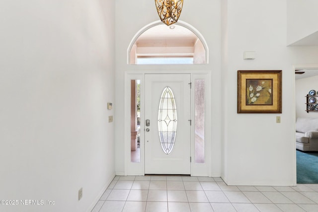 foyer entrance featuring light tile patterned floors, a high ceiling, and baseboards