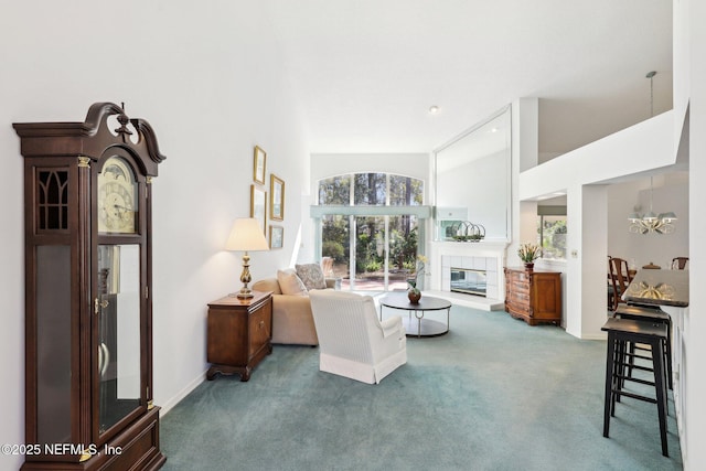 carpeted living area featuring a chandelier, high vaulted ceiling, a fireplace, and baseboards