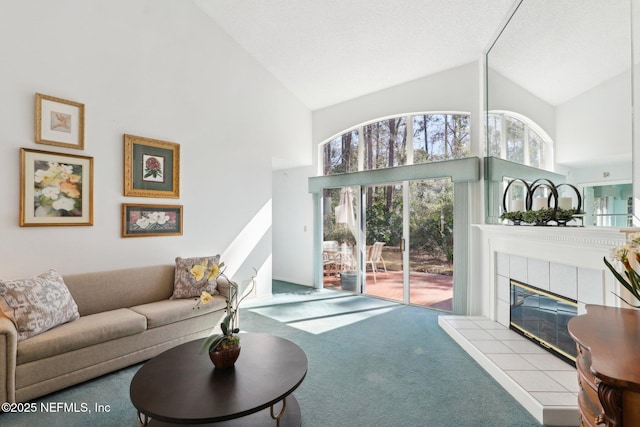 living area featuring a tiled fireplace, high vaulted ceiling, and carpet