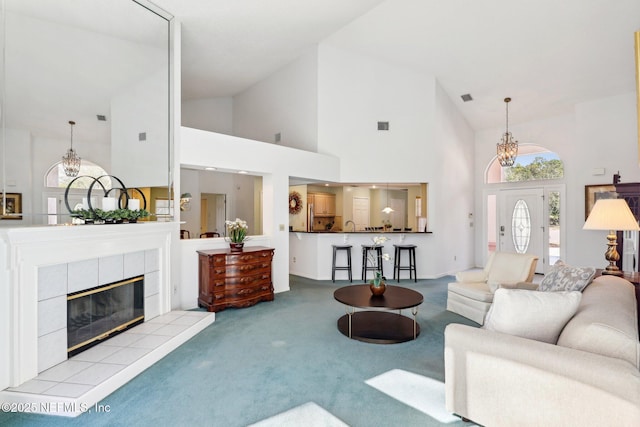 living area with carpet, visible vents, a fireplace, and an inviting chandelier