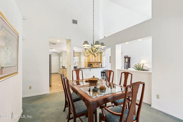 dining area featuring a high ceiling, carpet floors, and an inviting chandelier