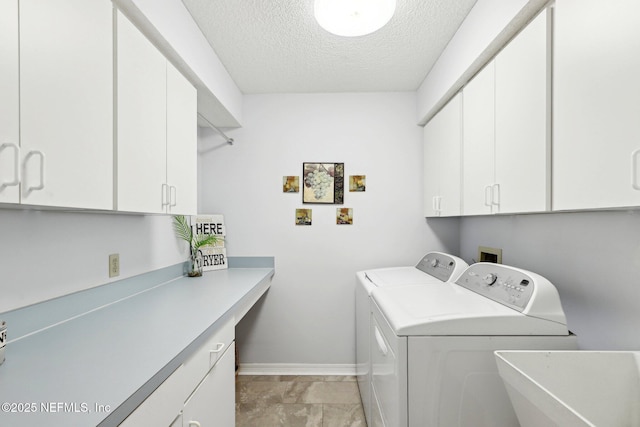 clothes washing area with a textured ceiling, separate washer and dryer, a sink, baseboards, and cabinet space