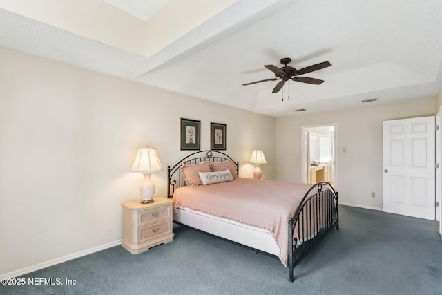 bedroom with baseboards, visible vents, dark colored carpet, and a tray ceiling