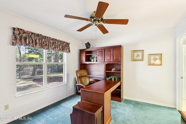 carpeted home office with ceiling fan and baseboards