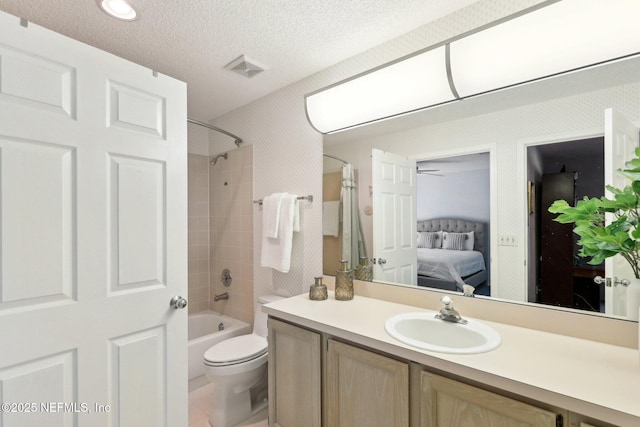 full bathroom featuring vanity, tiled shower / bath combo, toilet, and a textured ceiling