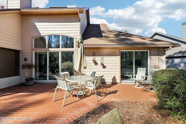 rear view of property featuring a shingled roof and a patio area