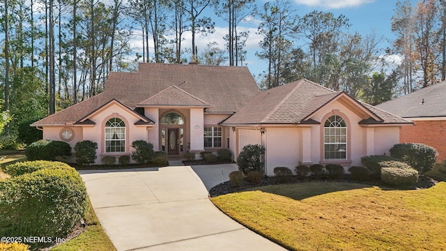 view of front of house with a garage, concrete driveway, a front lawn, and stucco siding