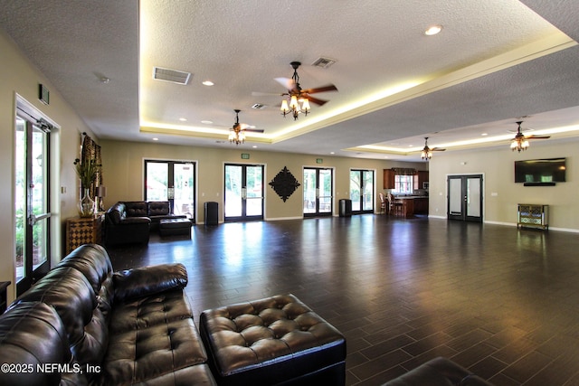 living room with a tray ceiling, dark hardwood / wood-style floors, and a textured ceiling