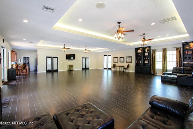 living room with ceiling fan and a tray ceiling