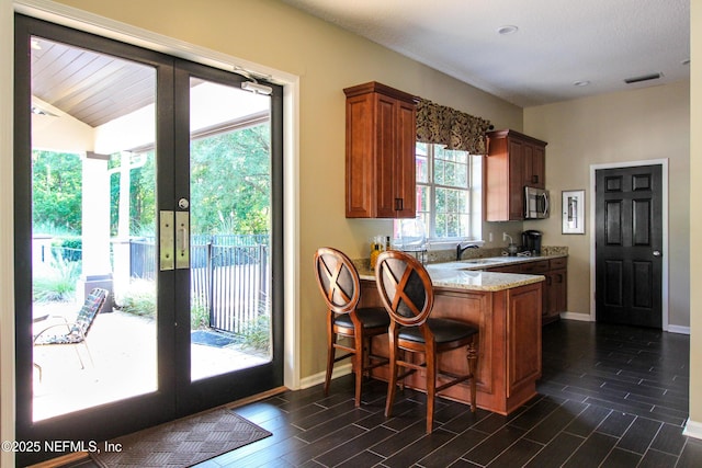 kitchen with visible vents, french doors, stainless steel microwave, light stone counters, and wood finish floors