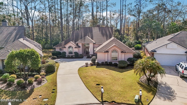 view of front of property featuring a garage, concrete driveway, a front lawn, and stucco siding