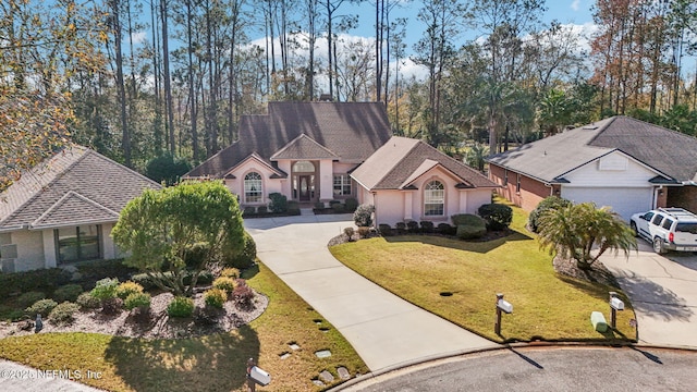 view of front facade with stucco siding, concrete driveway, and a front yard