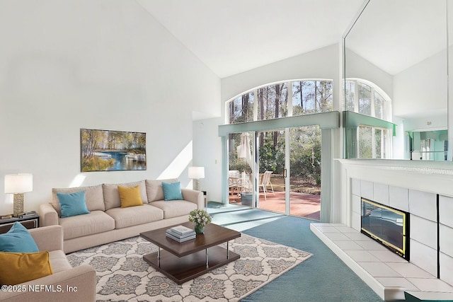 carpeted living room featuring high vaulted ceiling and a tiled fireplace