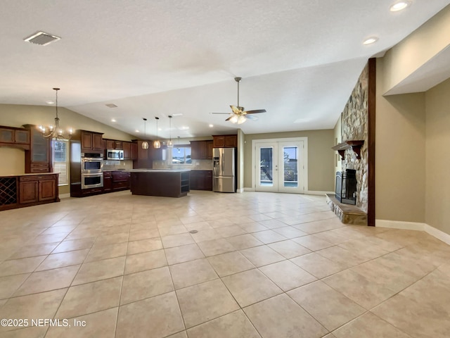 kitchen featuring decorative light fixtures, lofted ceiling, a center island, light tile patterned floors, and stainless steel appliances