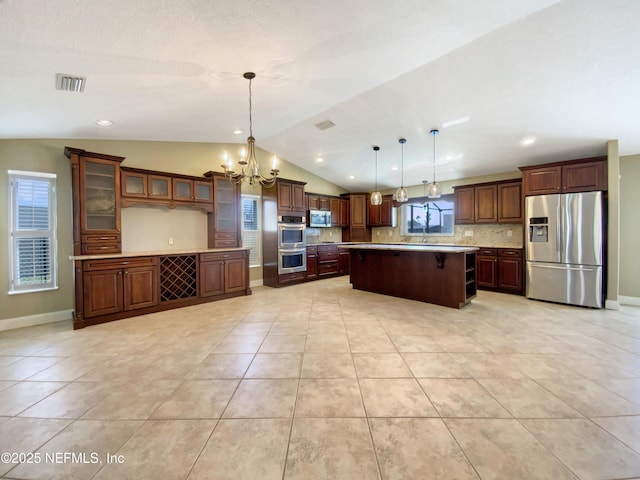 kitchen with a center island, light tile patterned floors, appliances with stainless steel finishes, pendant lighting, and backsplash