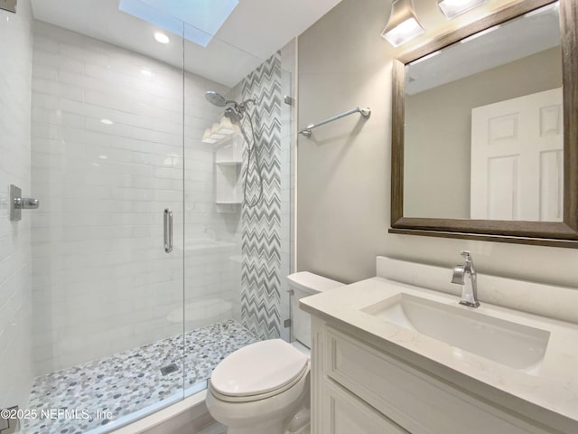 bathroom featuring a skylight, vanity, toilet, and an enclosed shower