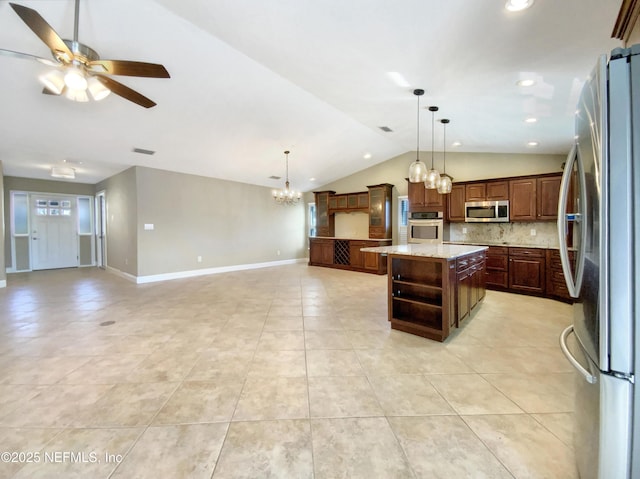 kitchen featuring pendant lighting, lofted ceiling, a kitchen island with sink, stainless steel appliances, and tasteful backsplash