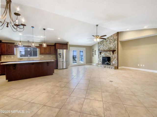 kitchen featuring decorative light fixtures, a center island, vaulted ceiling, stainless steel fridge with ice dispenser, and backsplash