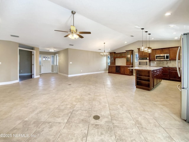 kitchen with lofted ceiling, hanging light fixtures, stainless steel appliances, a kitchen island, and decorative backsplash