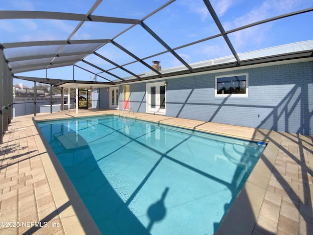 view of swimming pool featuring french doors, a patio area, and glass enclosure