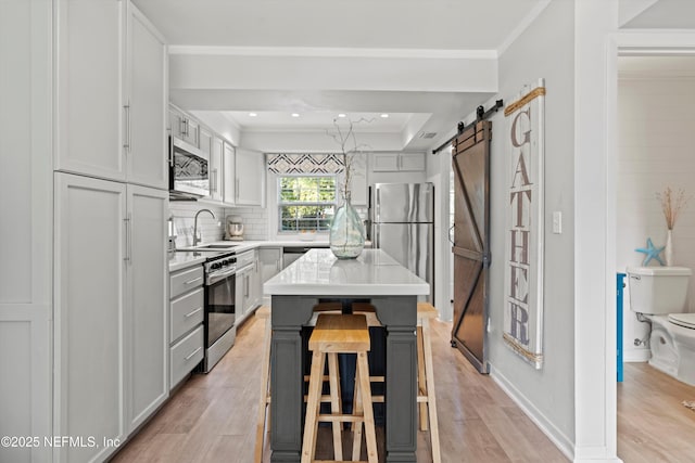 kitchen with sink, stainless steel appliances, a center island, a kitchen bar, and a barn door