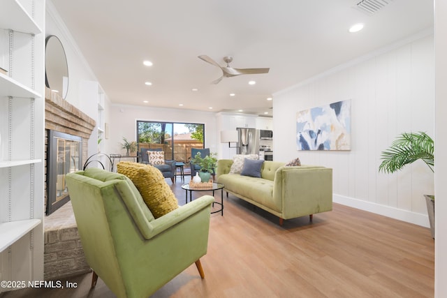 living room with crown molding, light hardwood / wood-style flooring, and ceiling fan