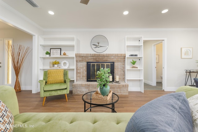 living room featuring a brick fireplace, crown molding, light hardwood / wood-style floors, and built in shelves