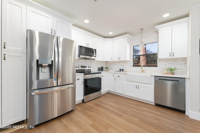 kitchen with sink, decorative light fixtures, white cabinets, and appliances with stainless steel finishes