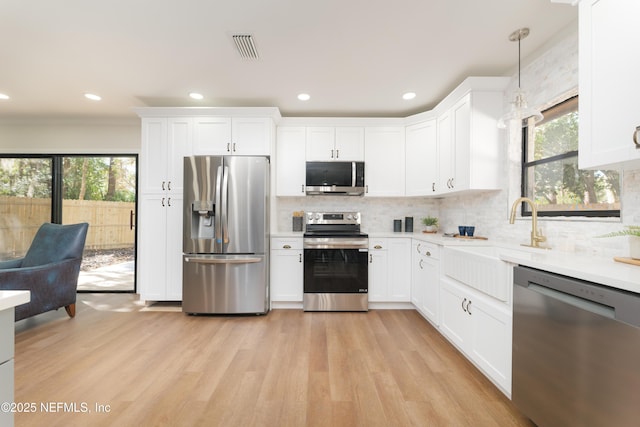 kitchen with hanging light fixtures, appliances with stainless steel finishes, and white cabinets