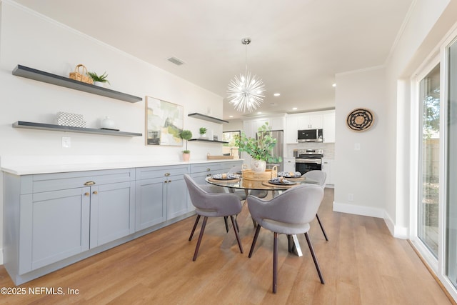 dining space with ornamental molding, a chandelier, and light hardwood / wood-style floors