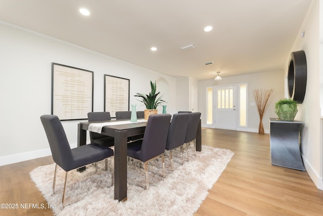 dining space featuring ornamental molding and light wood-type flooring