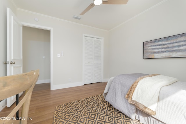 bedroom with hardwood / wood-style flooring, ornamental molding, a closet, and ceiling fan