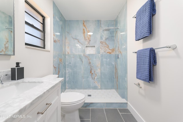 bathroom featuring tile patterned flooring, vanity, tiled shower, and toilet