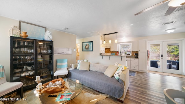 living room with ceiling fan, dark wood-type flooring, a textured ceiling, and french doors