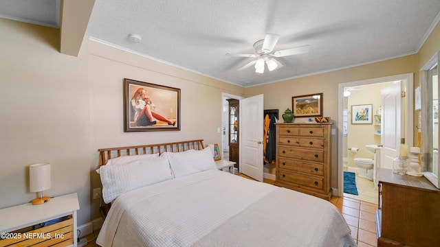 tiled bedroom featuring ornamental molding, ceiling fan, a textured ceiling, and ensuite bath