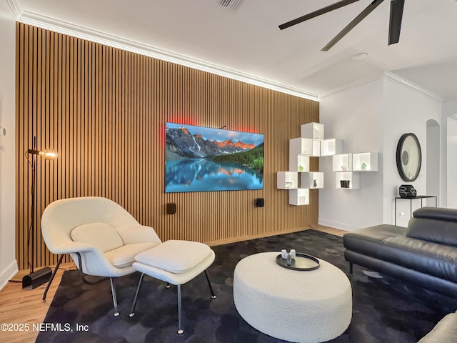 interior space featuring hardwood / wood-style flooring, crown molding, ceiling fan, and wooden walls